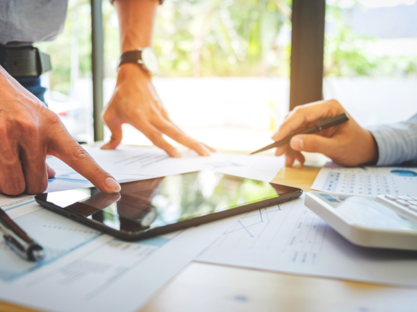 Hände von zwei Personen, die auf ein Tablet zeigen